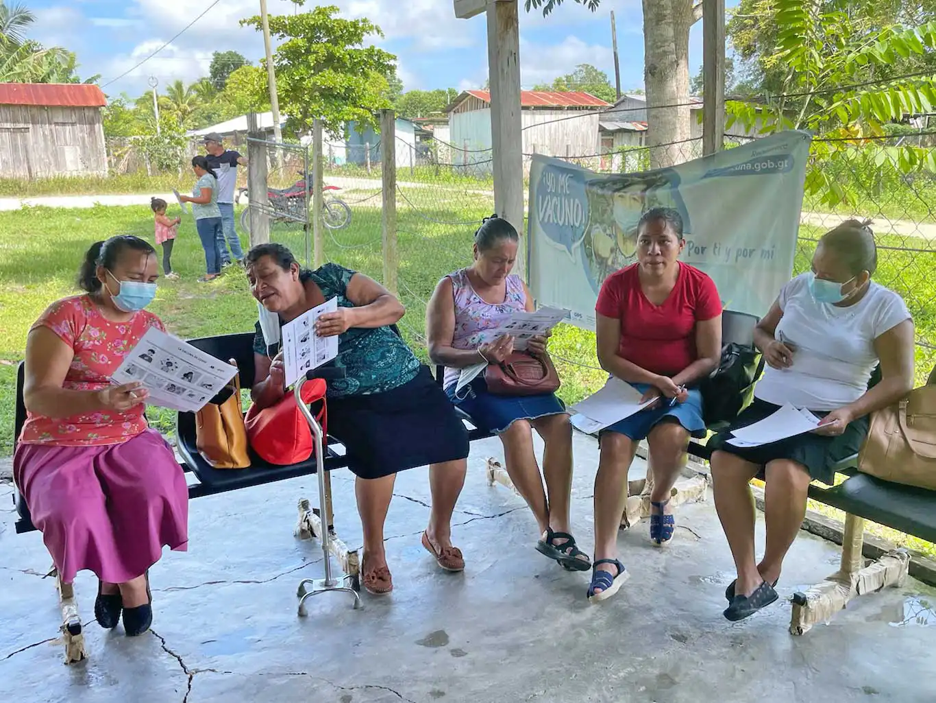 Midwives review documents in an outdoor seating area