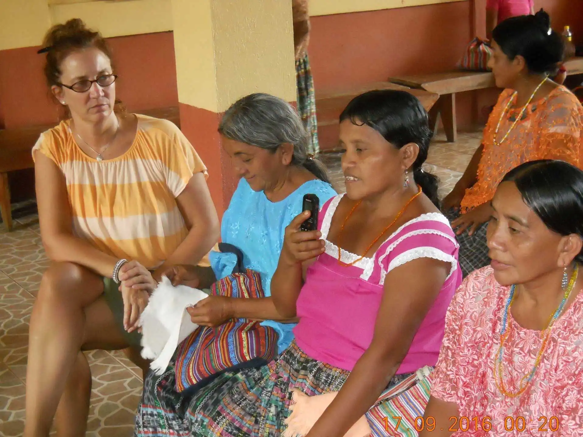 Kimberly sits alongside midwives, one of whom holds up a recording device