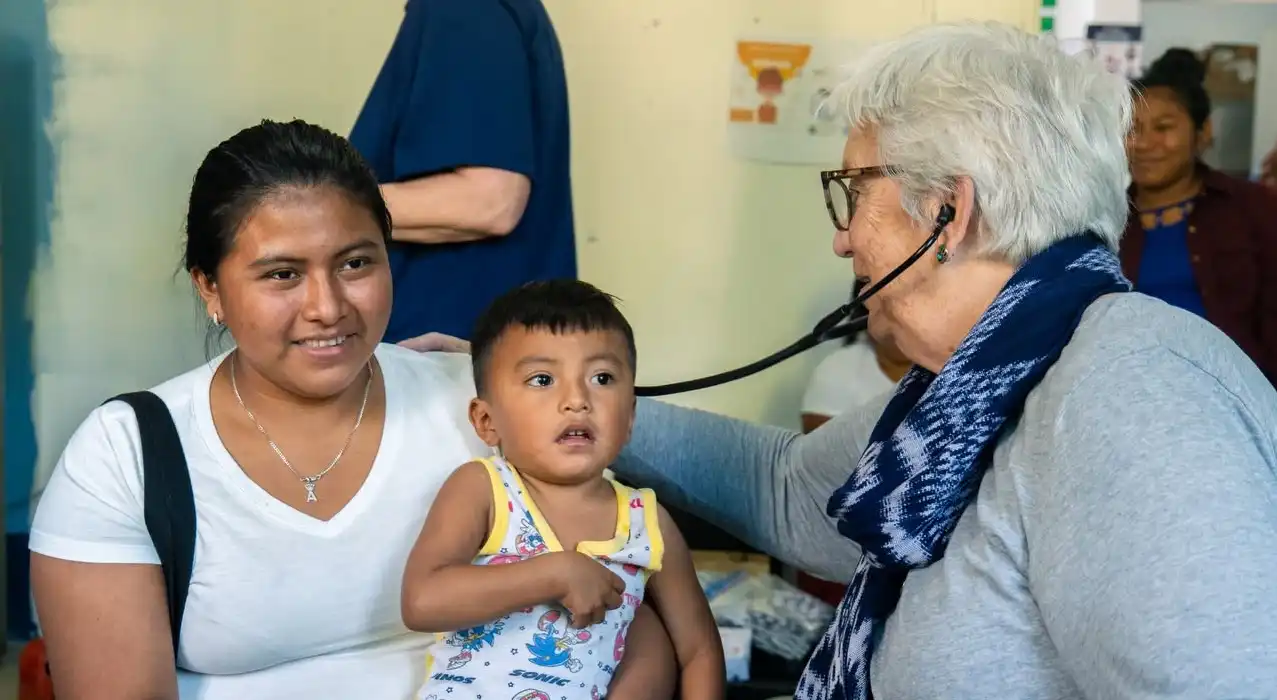 Deborah Bell listens to the heart of a mother with a child in her lap